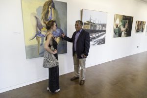 La ganadora del premio del año pasado conversa con uno de los organizadores en la exposición de las obras